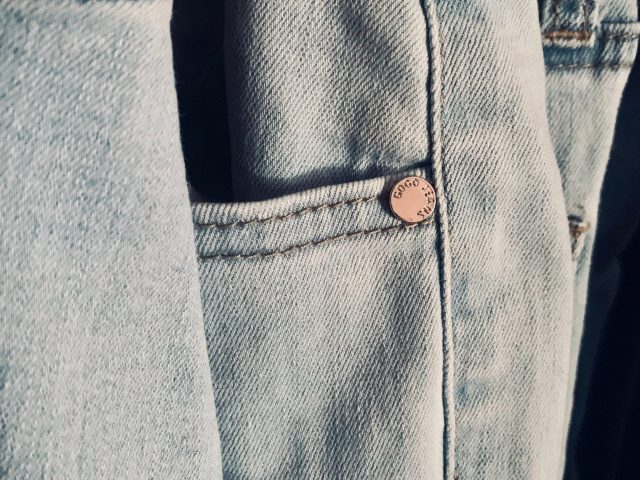 Ein Stapel heller Jeans, des Bild zeigt den Ausschnitt um die Hosentaschen